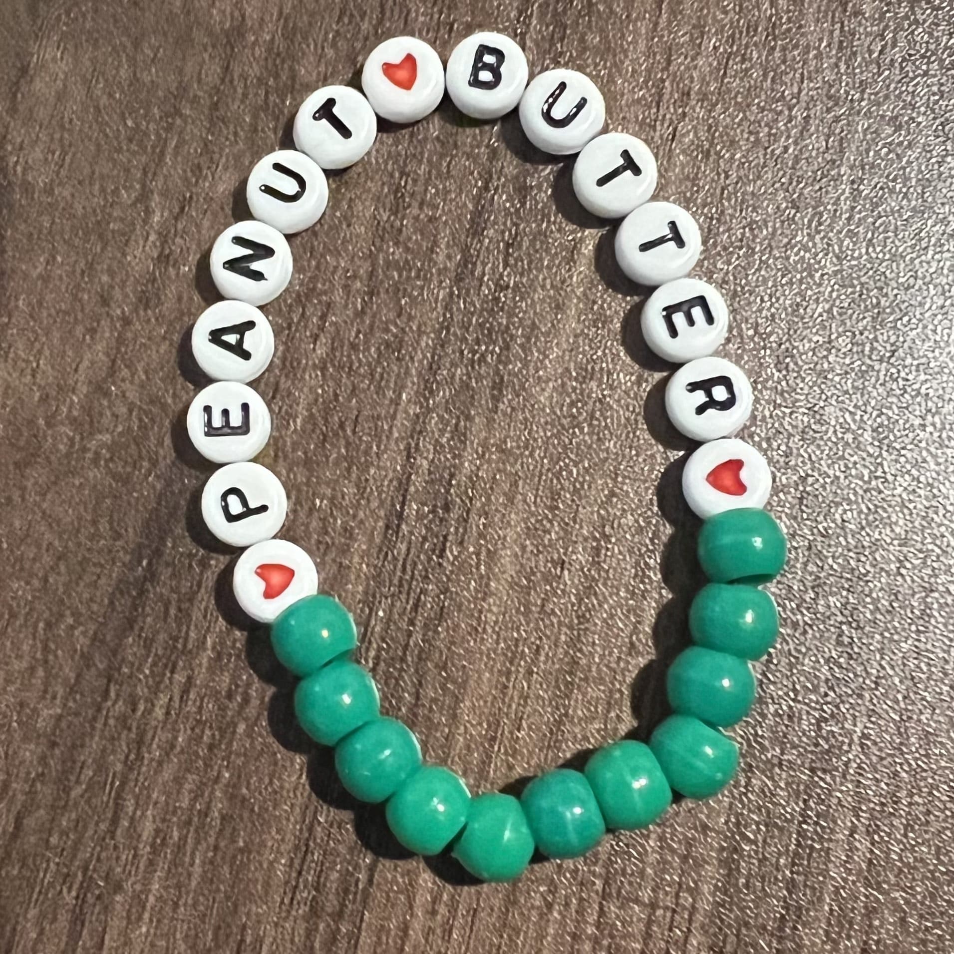 bracelet with green beads, heart beads, and beads that read 'peanut butter'